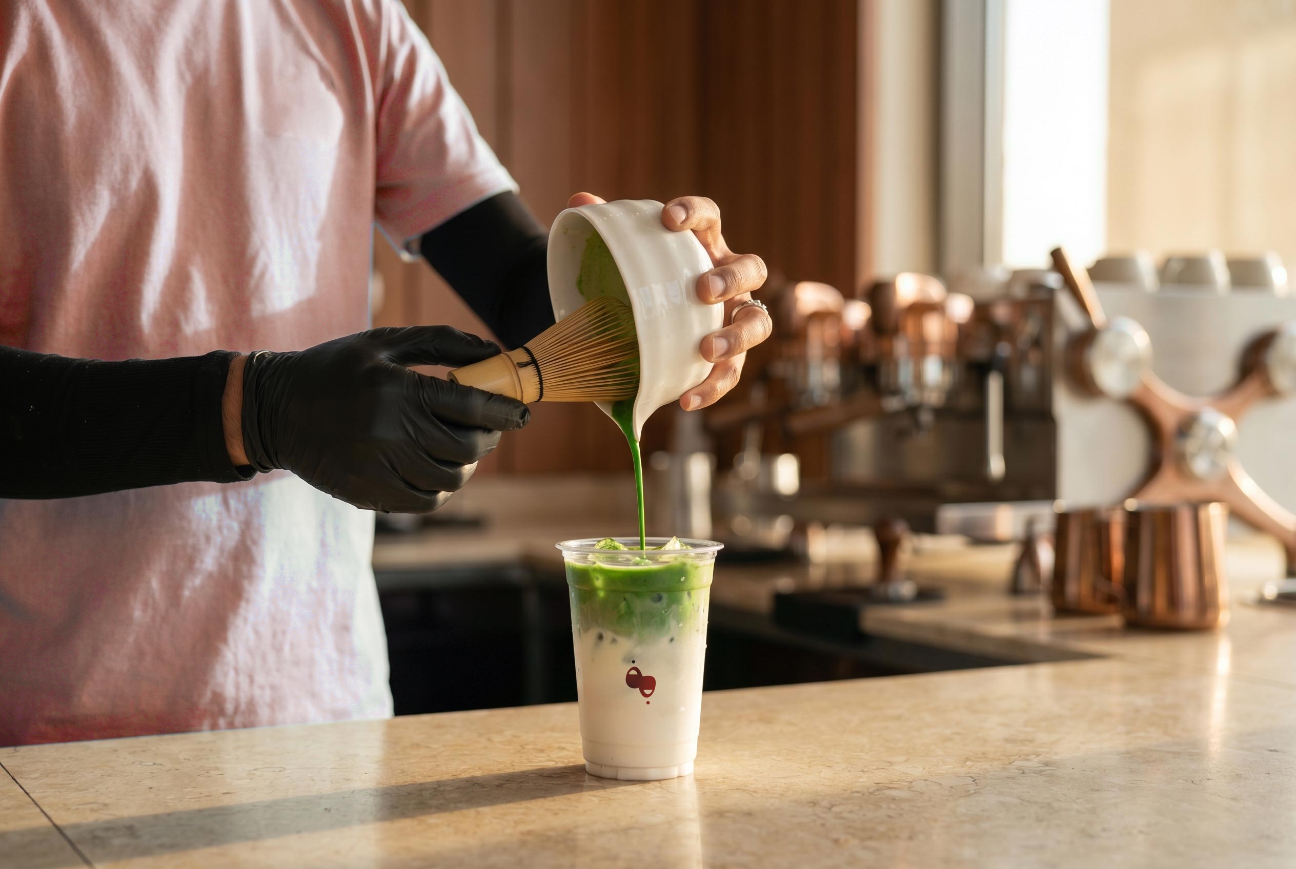 Barista whisking and pouring iced matcha